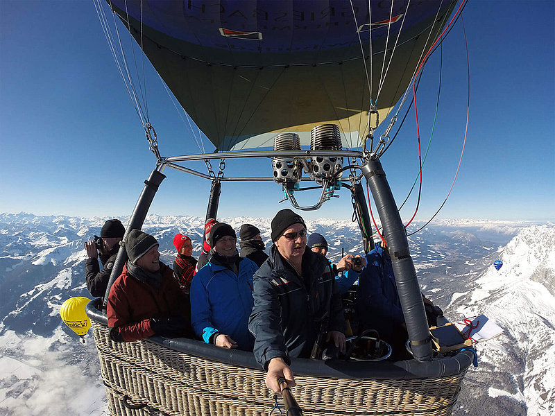 Großer Ballonkorb mit vielen Passagieren über den Alpen